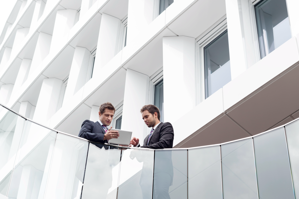 Two men having a discussion in the balcony of a tall building