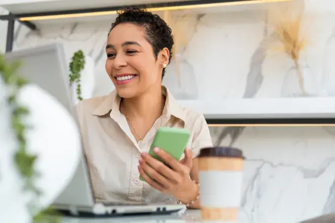 smiling woman using laptop and cell phone
