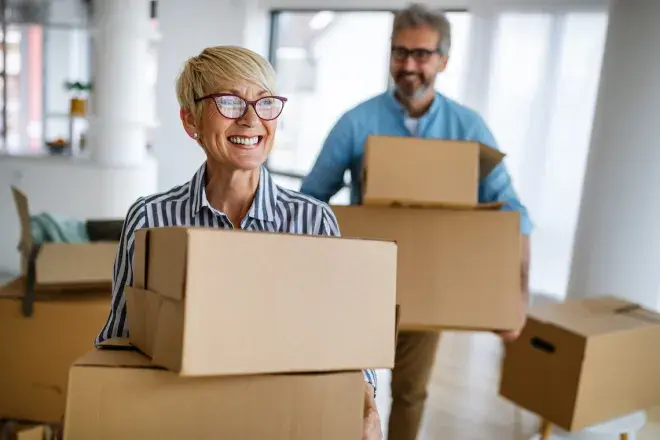 happy senior couple moving boxes into new home